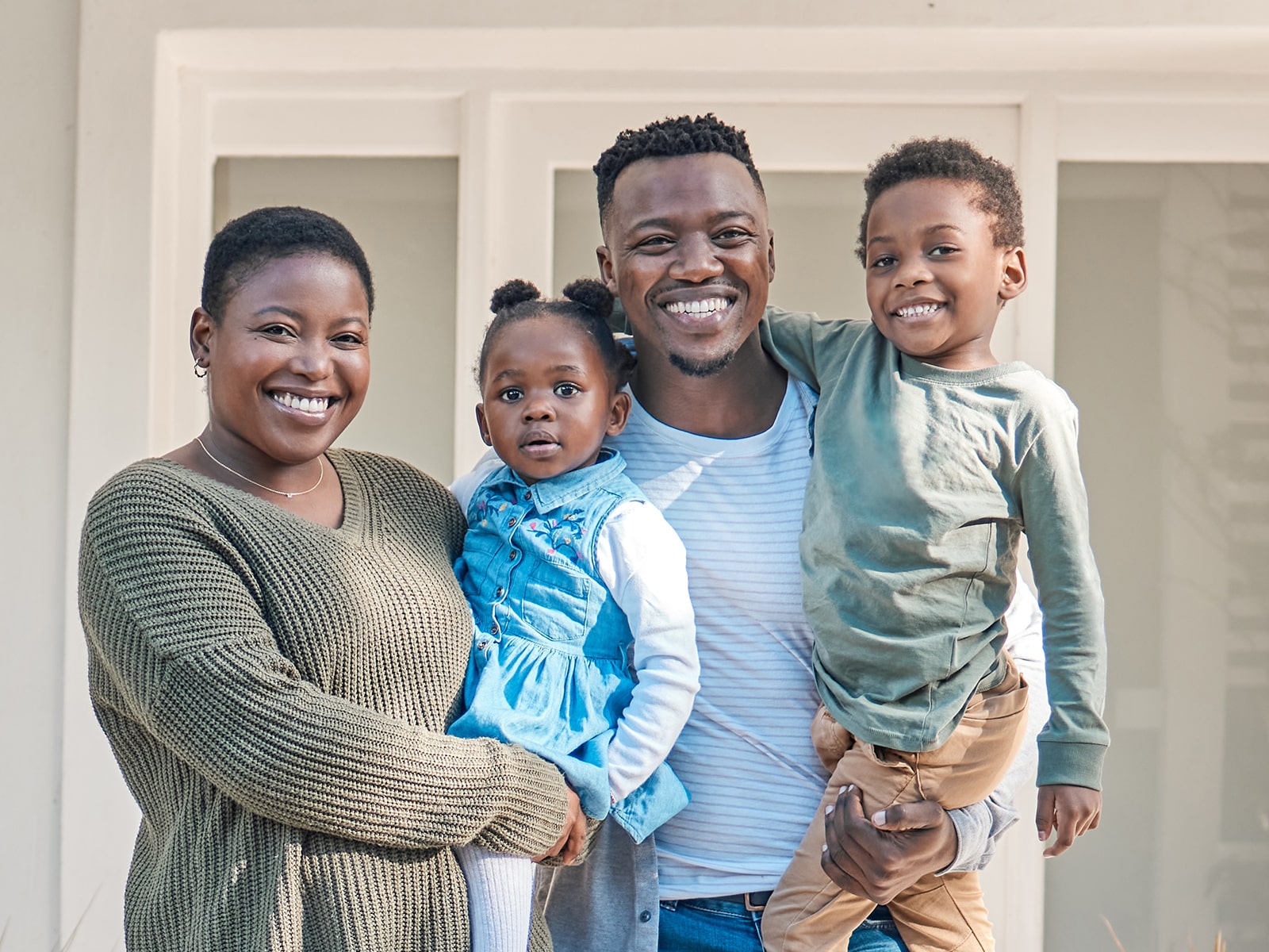 Family smiling in front of home